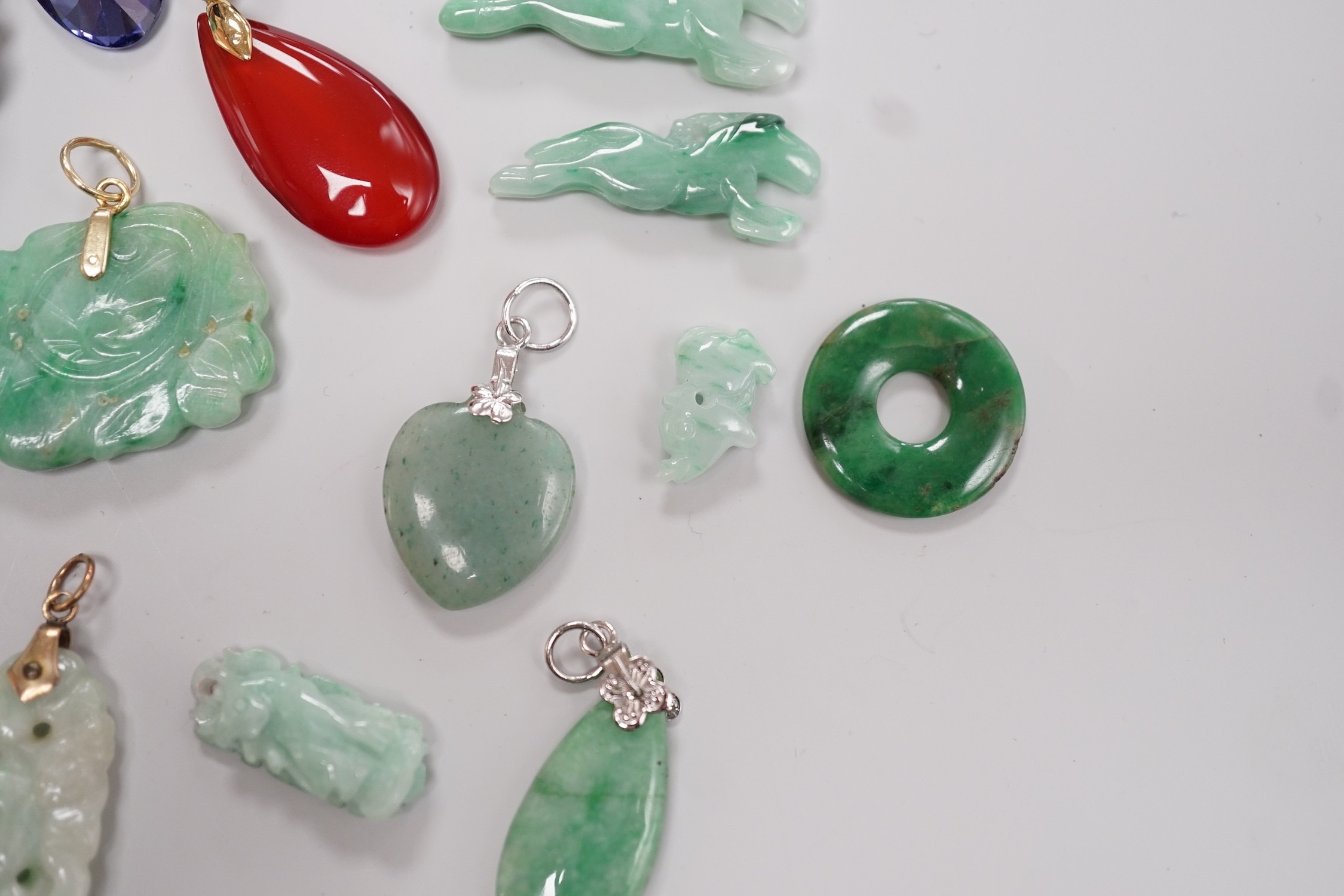 Twelve assorted carved jadeite items including five pendants, largest 40mm, a 14k mounted carnelian pendant and an unmounted pear cut simulated Tanzanite.